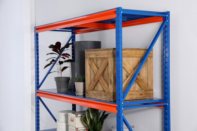 Photo of Metal shelving unit with different household stuff on light background