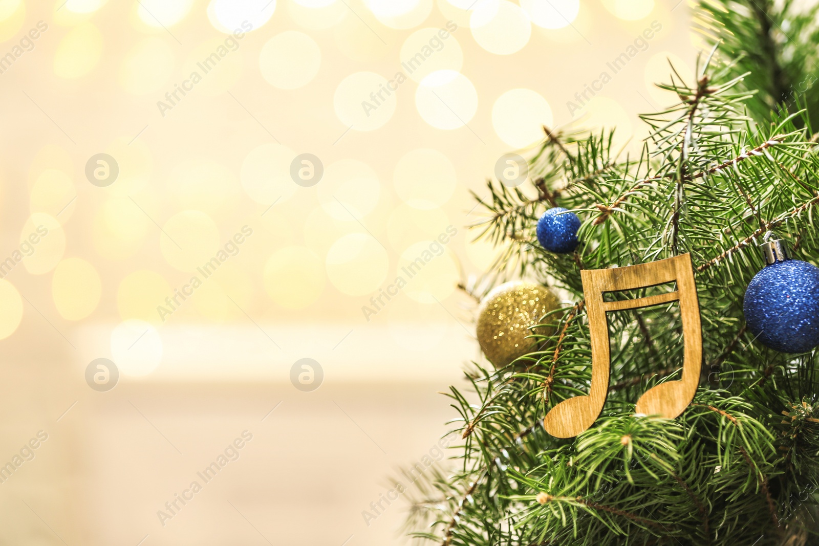 Photo of Fir tree with wooden music notes and space for text against blurred Christmas lights