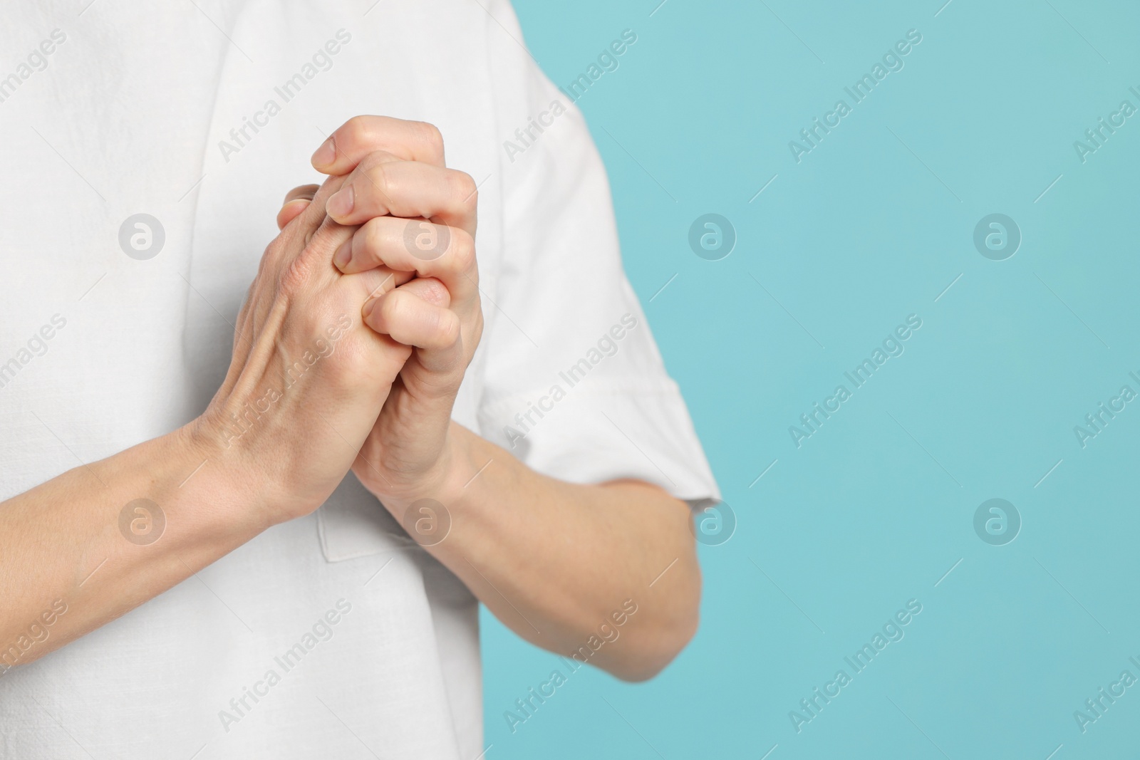 Photo of Woman cracking her knuckles on turquoise background, closeup and space for text. Bad habit