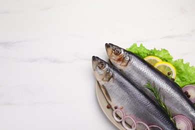 Photo of Plate with salted herrings, onion rings, slices of lemon, peppercorns and lettuce on white marble table, top view. Space for text