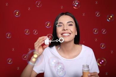 Young woman blowing soap bubbles on red background