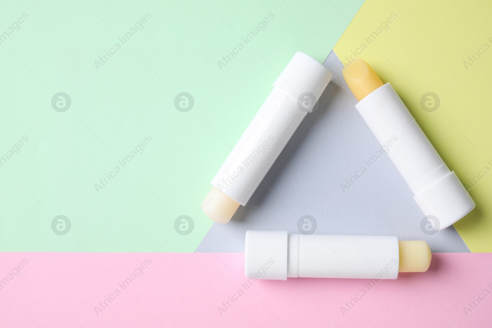 Photo of Hygienic lipsticks on color background, flat lay. Space for text