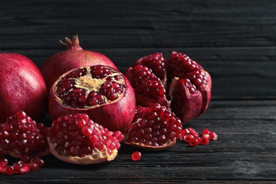 Photo of Ripe pomegranates and seeds on wooden table