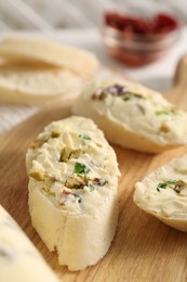 Photo of Tasty butter with olives, green onion and bread on wooden board, closeup