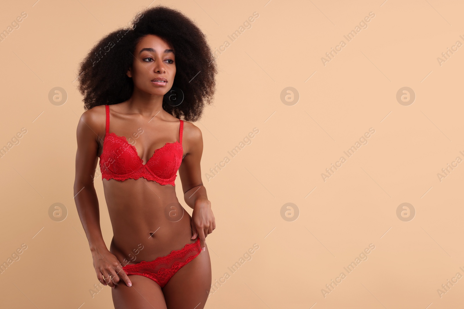 Photo of Beautiful woman in elegant red underwear on beige background, space for text