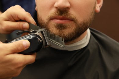Photo of Professional hairdresser working with client in barbershop, closeup 