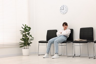 Photo of Woman sitting on chair and waiting for appointment indoors