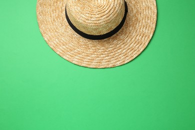 Photo of Stylish straw hat on green background, top view. Space for text