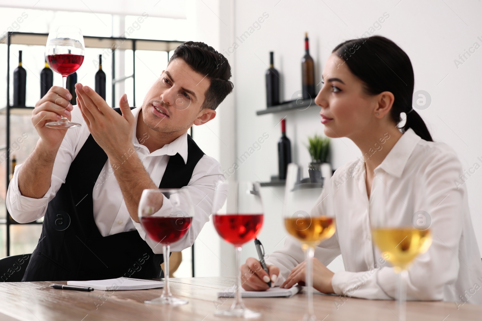 Photo of Sommeliers tasting different sorts of wine at table indoors