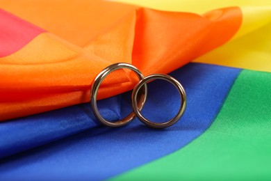 Wedding rings on rainbow LGBT flag, closeup