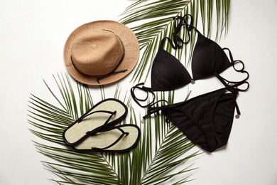 Photo of Flat lay composition with black swimsuit and beach accessories on light stone background