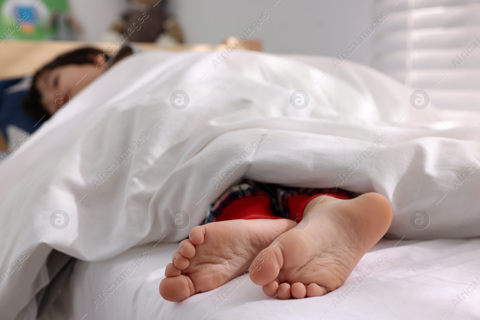 Photo of Little boy sleeping in bed at home, focus on feet