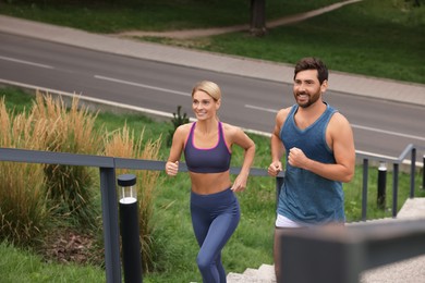 Photo of Healthy lifestyle. Happy couple running up stairs outdoors