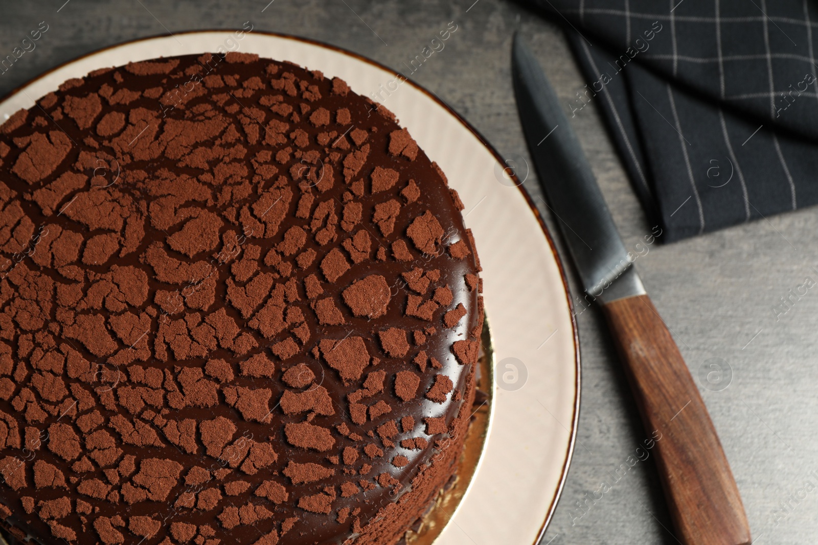 Photo of Delicious chocolate truffle cake and knife on grey textured table, above view