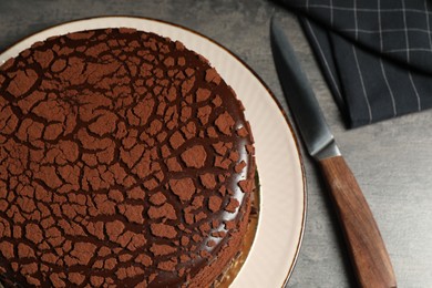 Photo of Delicious chocolate truffle cake and knife on grey textured table, above view