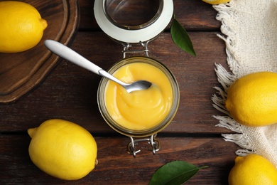 Delicious lemon curd and fresh fruits on wooden table, flat lay