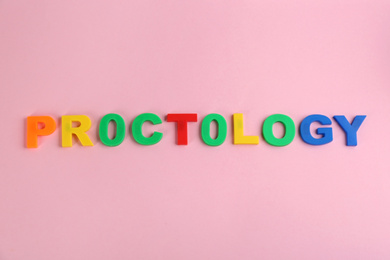 Photo of Word PROCTOLOGY made of colorful letters on pink background, flat lay. Hemorrhoid problems