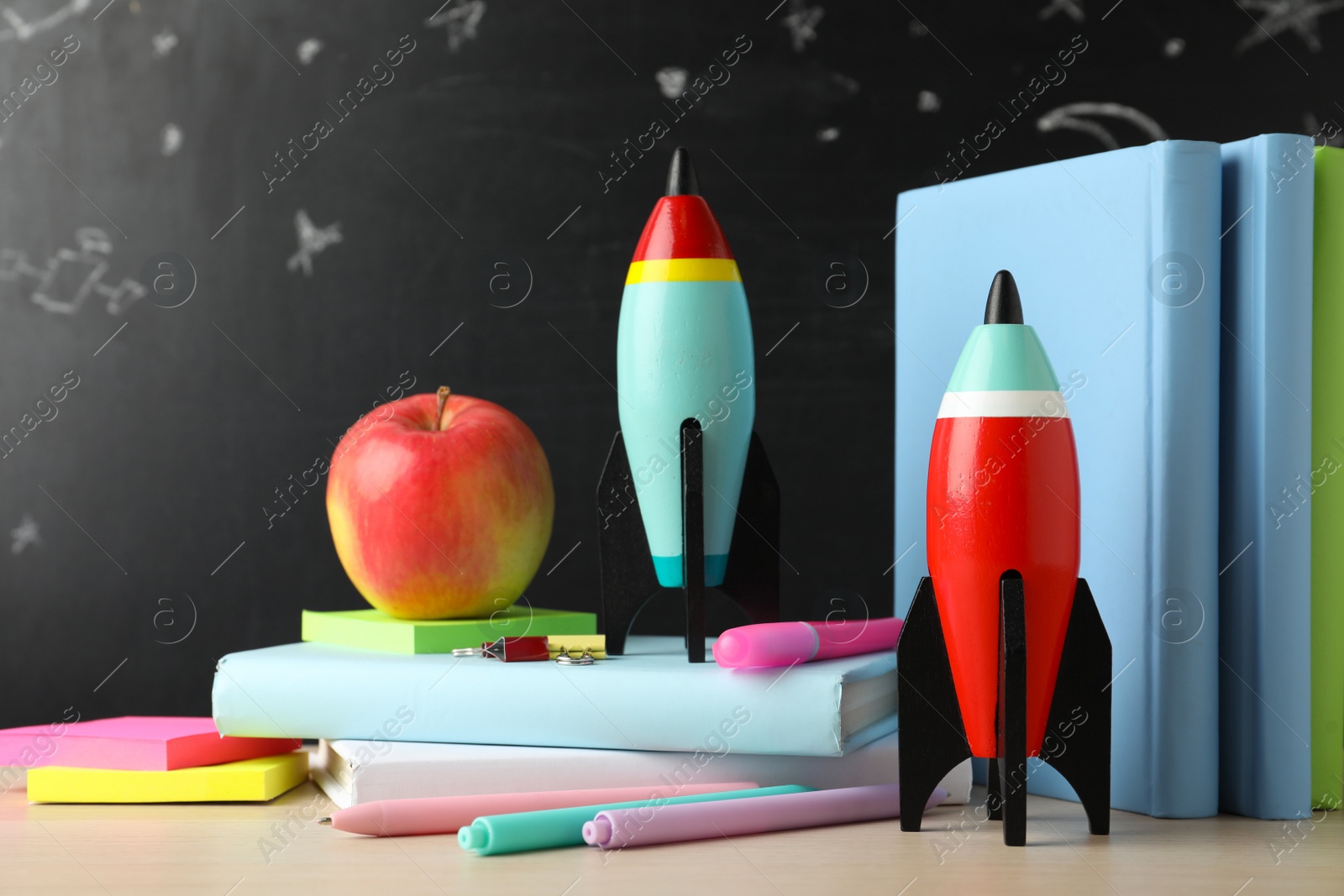 Photo of Bright toy rockets and school supplies on wooden table