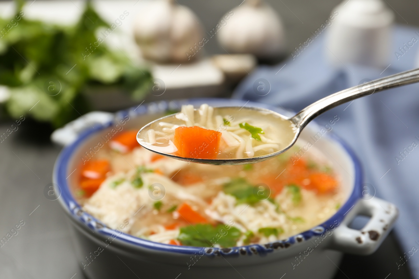 Photo of Spoon with fresh homemade chicken soup on blurred background, closeup