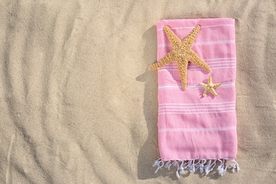 Photo of Starfishes and towel on sand, top view with space for text. Beach objects