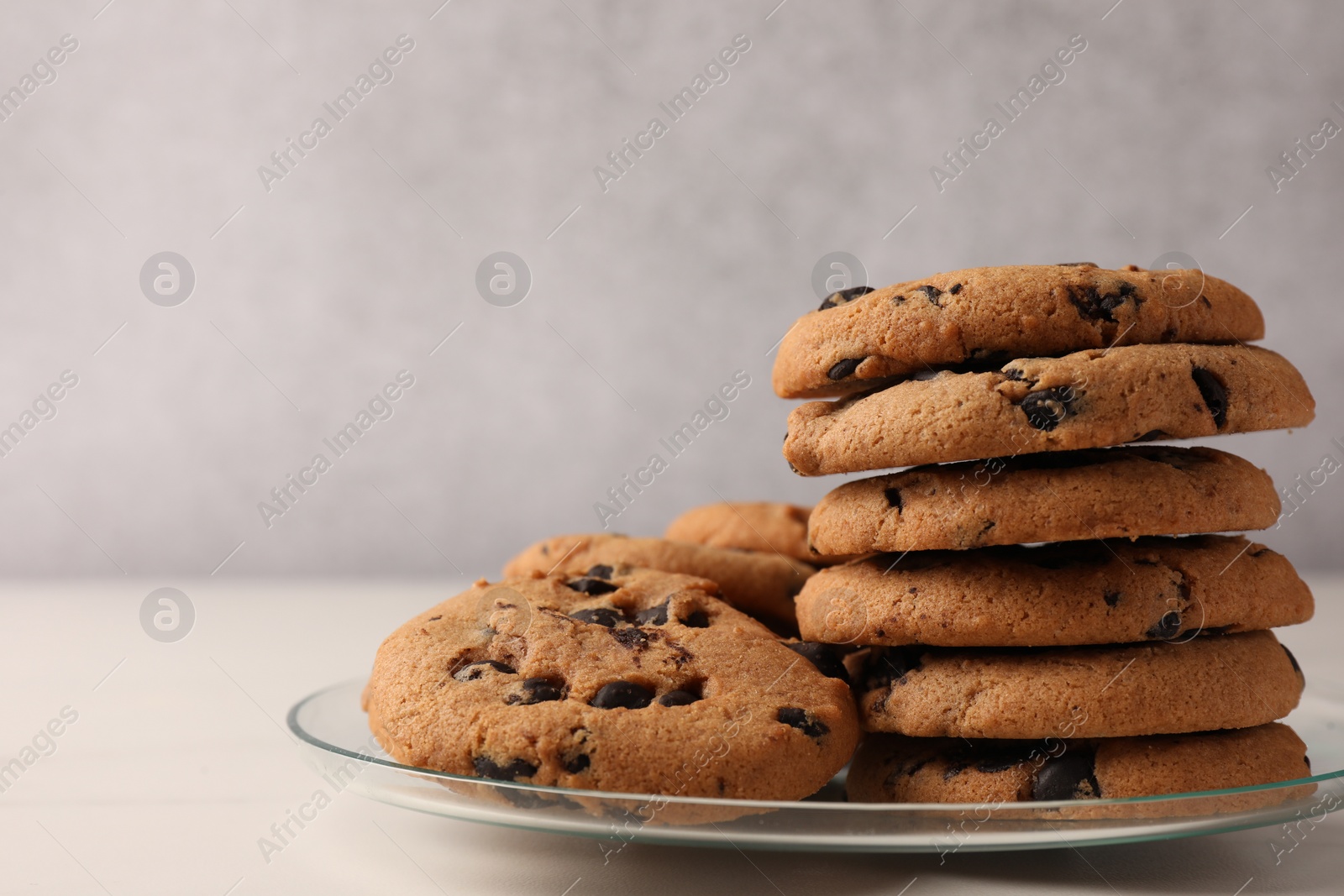 Photo of Delicious chocolate chip cookies on white marble table, closeup. Space for text