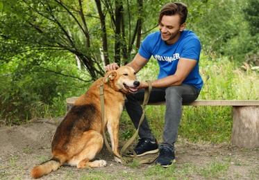 Photo of Male volunteer with homeless dog at animal shelter outdoors