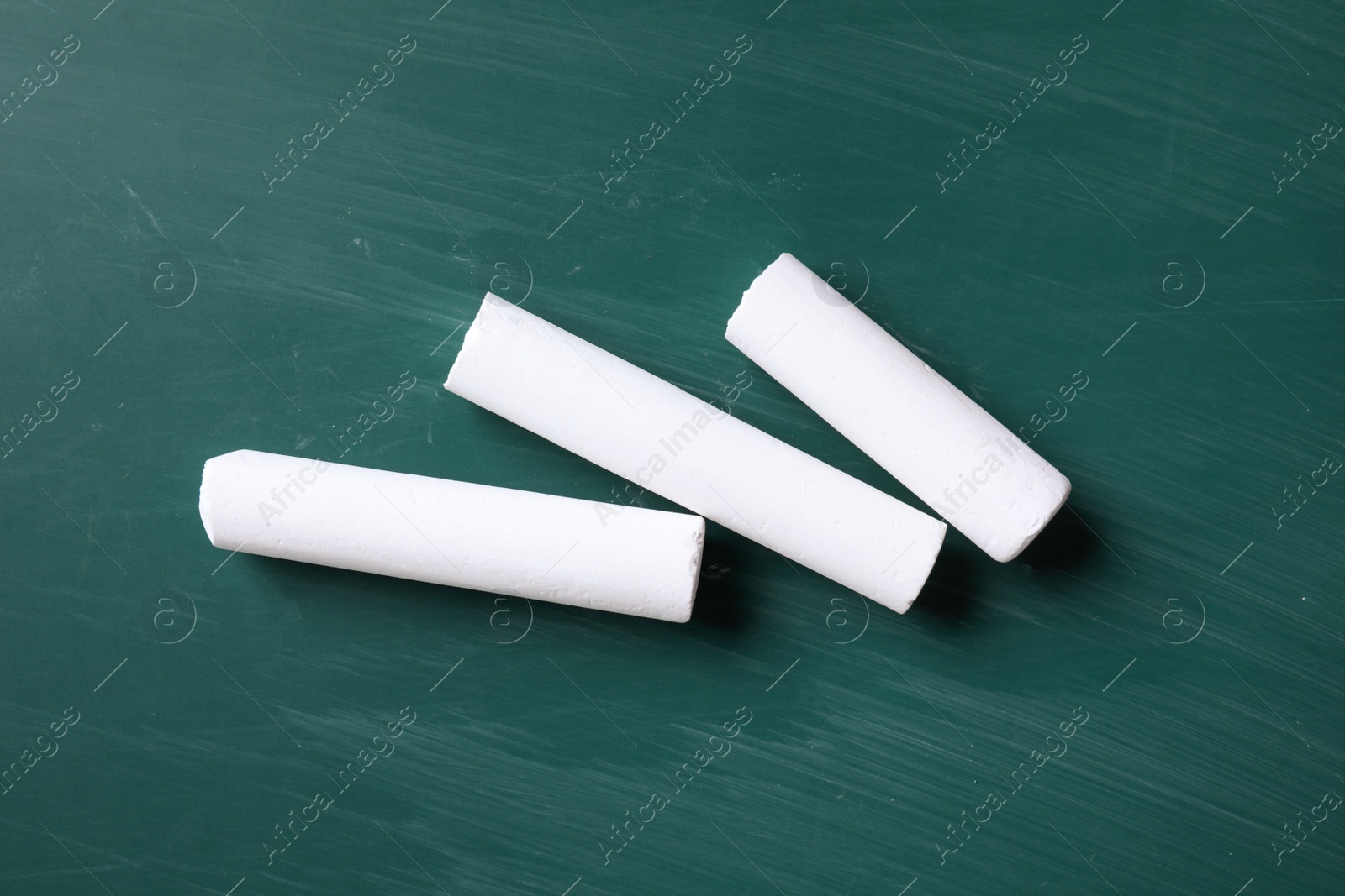 Photo of Pieces of white chalk on greenboard, flat lay