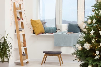 Beautiful shelf with Christmas accessories near cozy window sill in room. Interior design