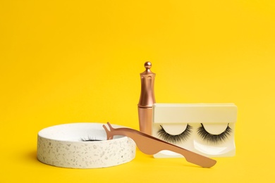 Photo of Magnetic eyelashes and accessories on yellow background