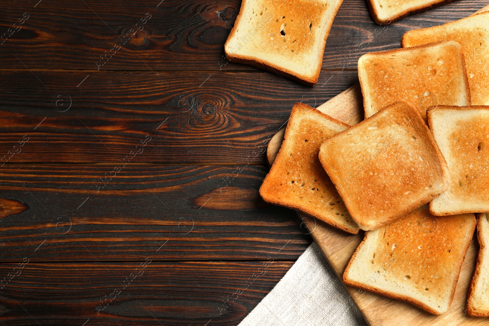 Photo of Slices of tasty toasted bread on wooden table, flat lay. Space for text