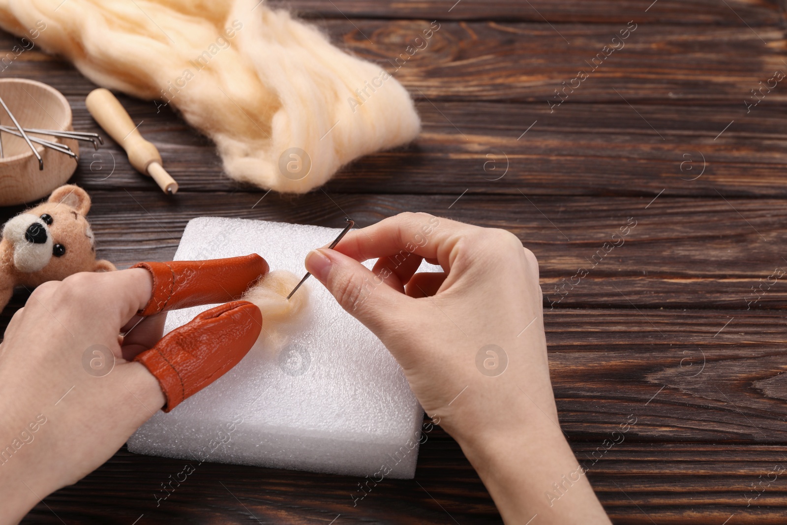 Photo of Woman felting from wool at wooden table, closeup. Space for text