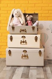 Storage trunks with different toys and picture near yellow brick wall indoors. interior design