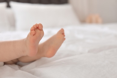 Photo of Cute little baby lying on bed, closeup of legs. Space for text