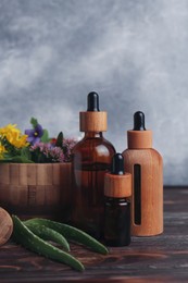 Glass bottles of aromatic essential oil and mortar with different herbs on wooden table