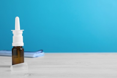 Photo of Nasal spray on white wooden table against light blue background. Space for text
