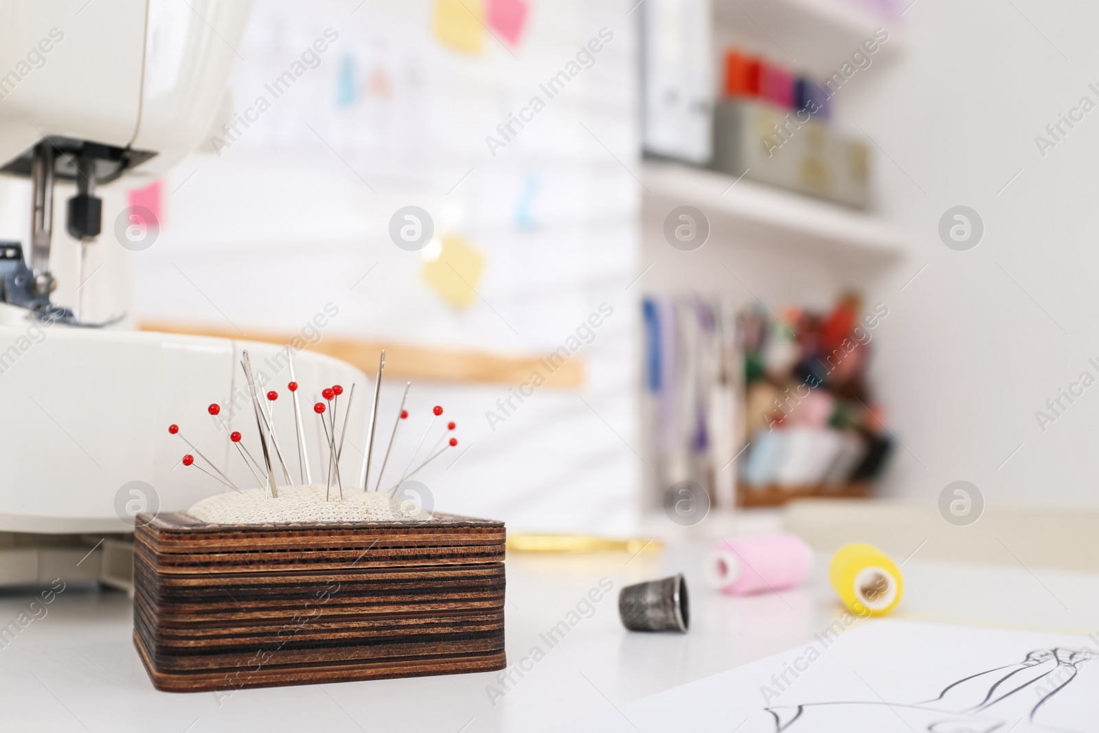 Photo of Different sewing accessories near modern machine in dressmaking workshop