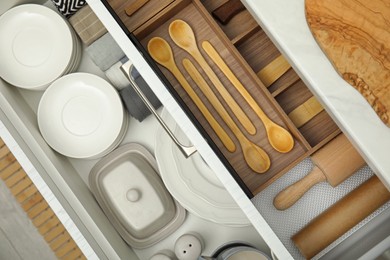 Photo of Open drawers of kitchen cabinet with different dishware and utensils, top view