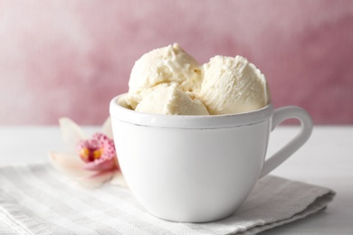 Photo of Cup with tasty vanilla ice cream on table