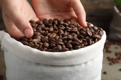 Photo of Woman taking roasted coffee beans from bag, closeup