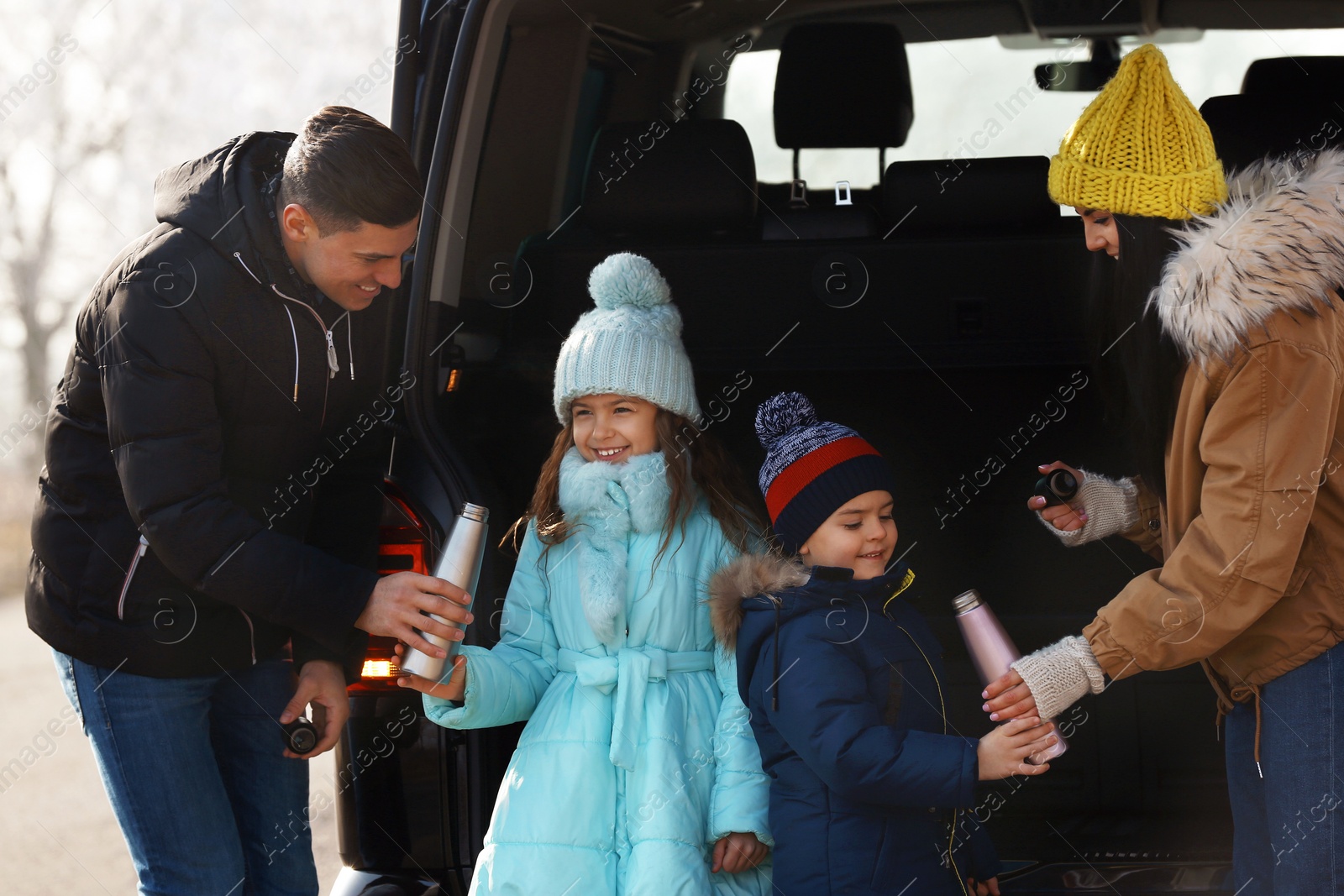 Photo of Happy family with little children near modern car on road