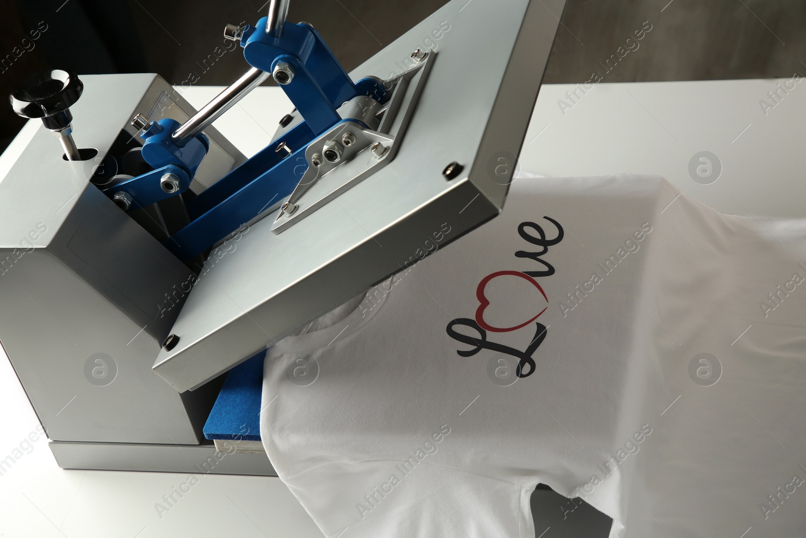 Photo of Printing logo. Heat press with t-shirt on white table