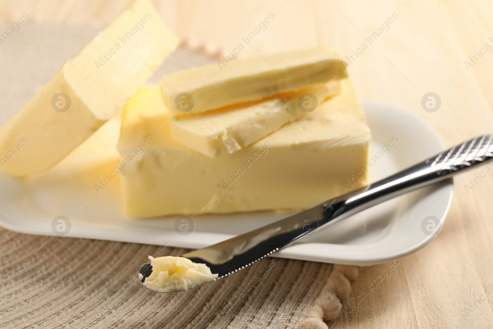 Photo of Tasty butter and knife on wooden table, closeup