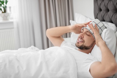 Photo of Man suffering from headache while lying on bed at home