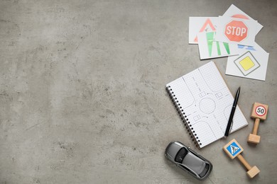 Photo of Many different road signs, notebook and toy car on grey background, flat lay with space for text. Driving school