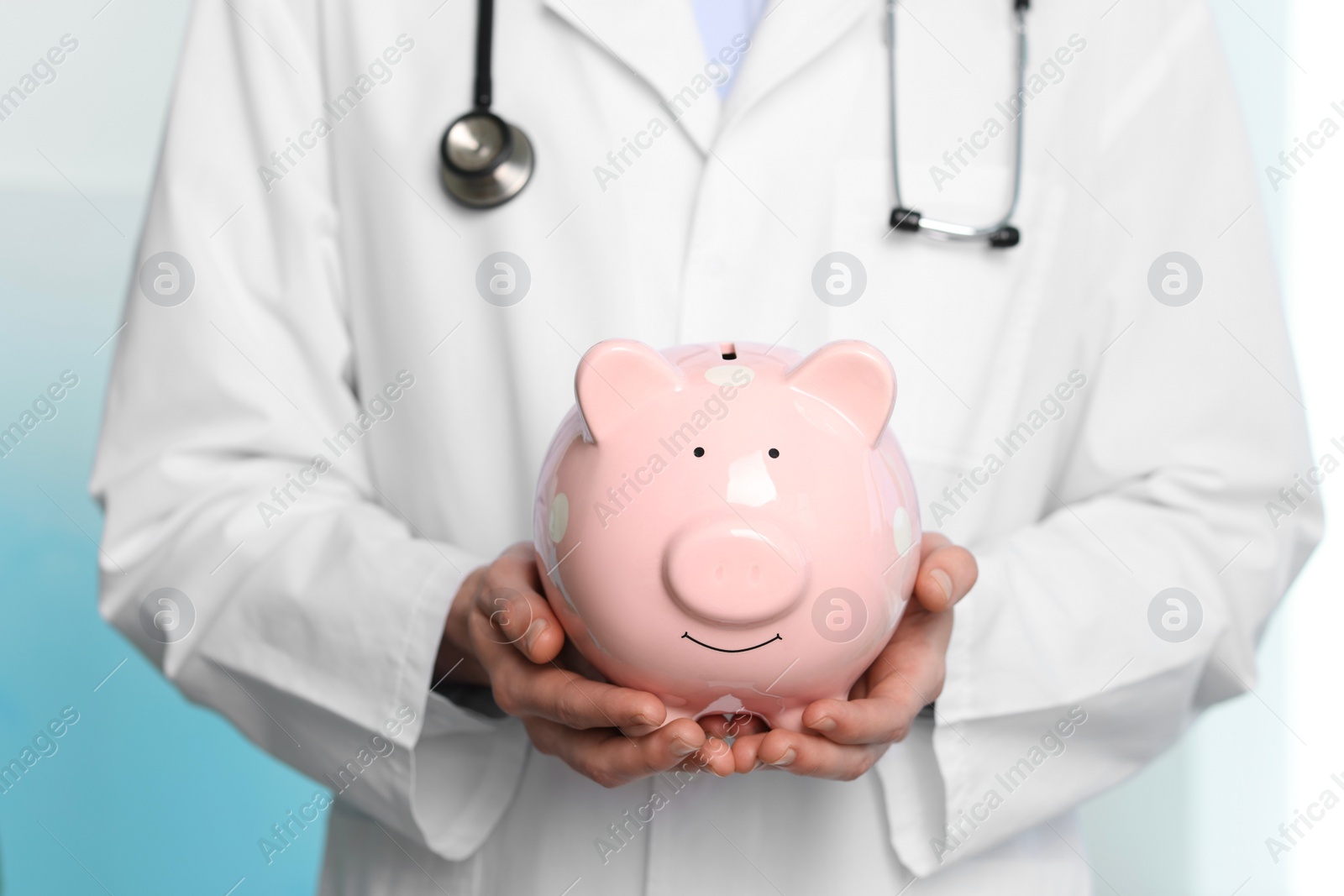 Photo of Doctor with piggy bank in hospital, closeup