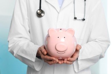 Photo of Doctor with piggy bank in hospital, closeup