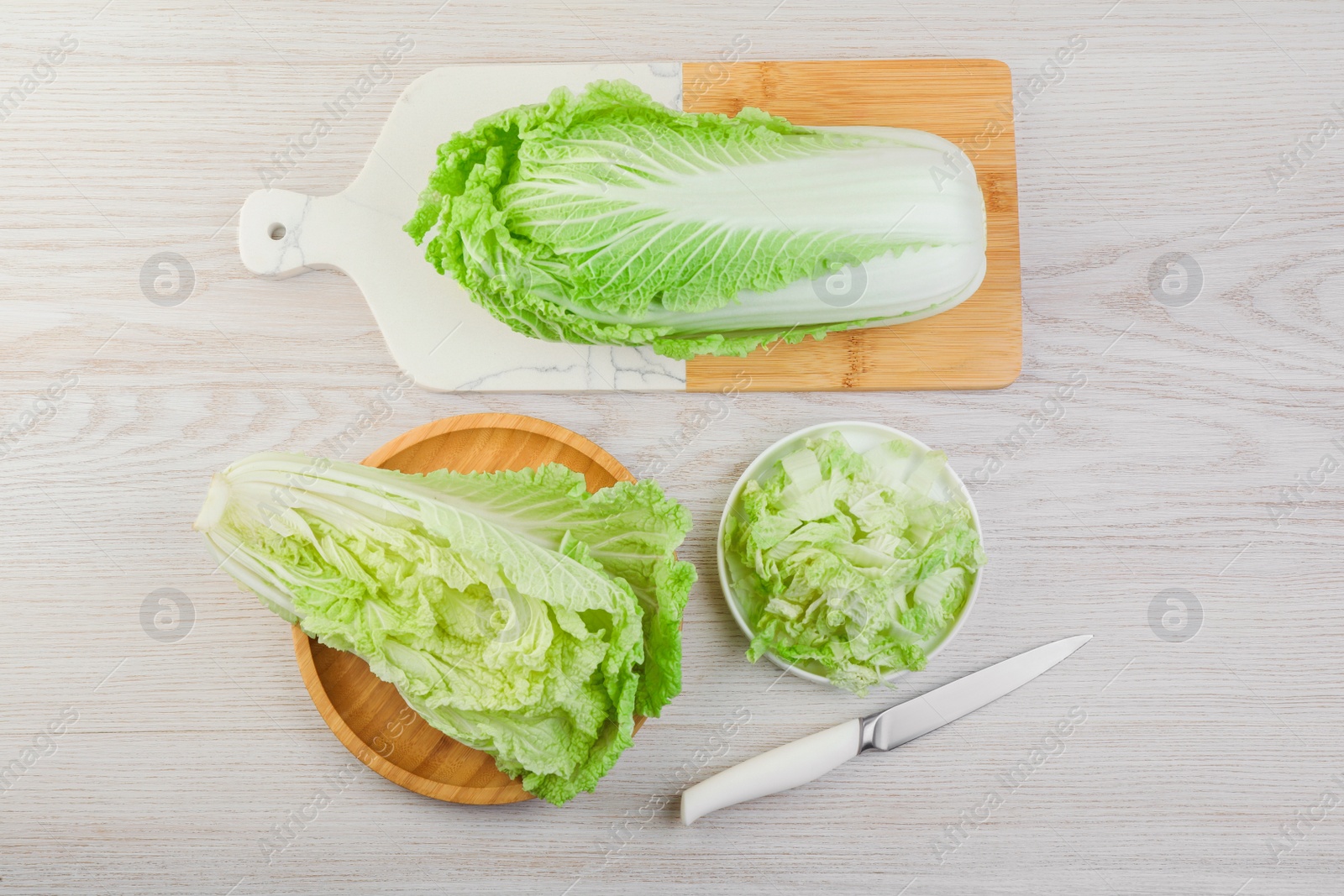 Photo of Whole and cut fresh ripe Chinese cabbage on white wooden table, flat lay