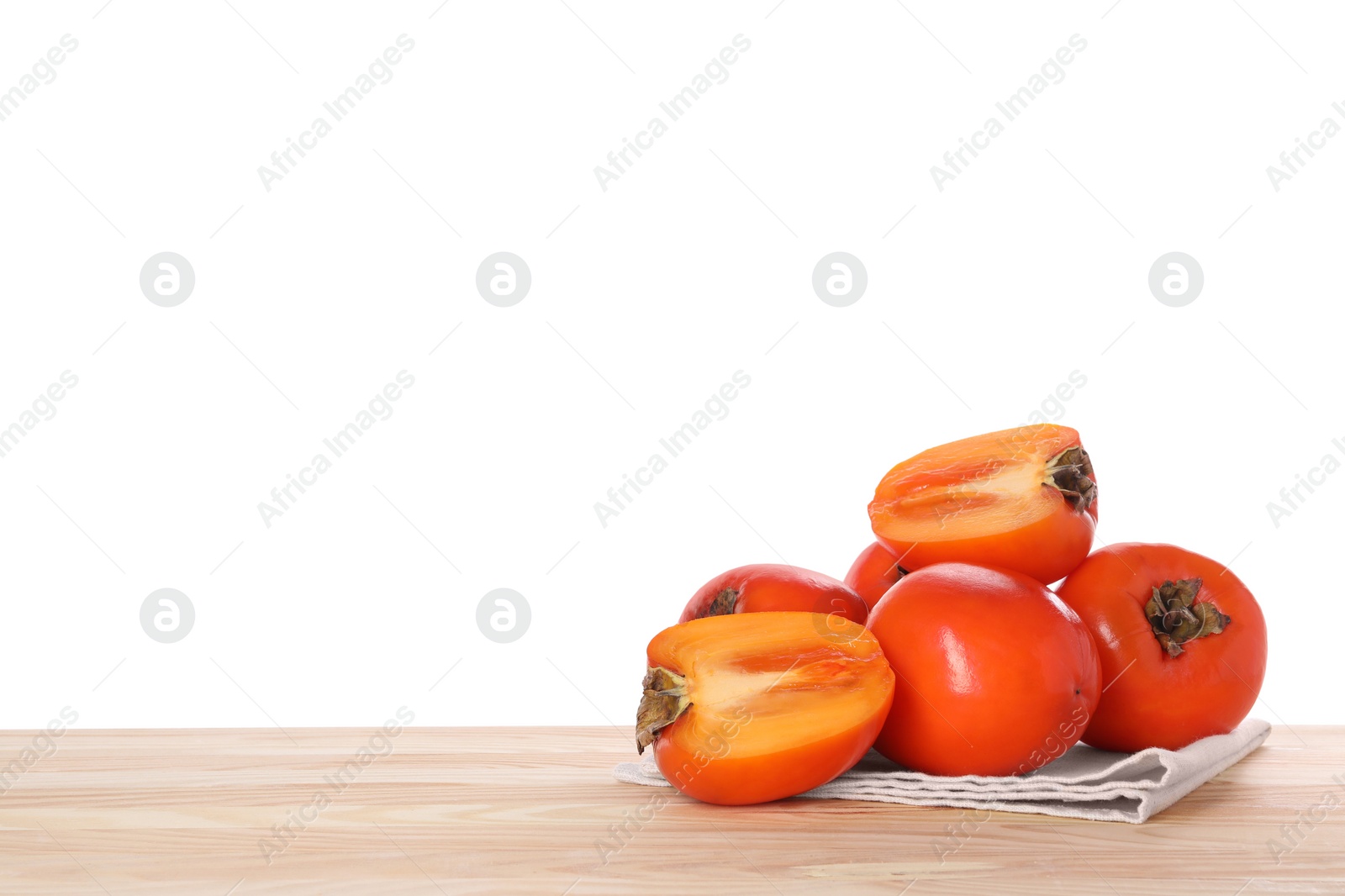 Photo of Delicious ripe juicy persimmons and napkin on wooden table against white background