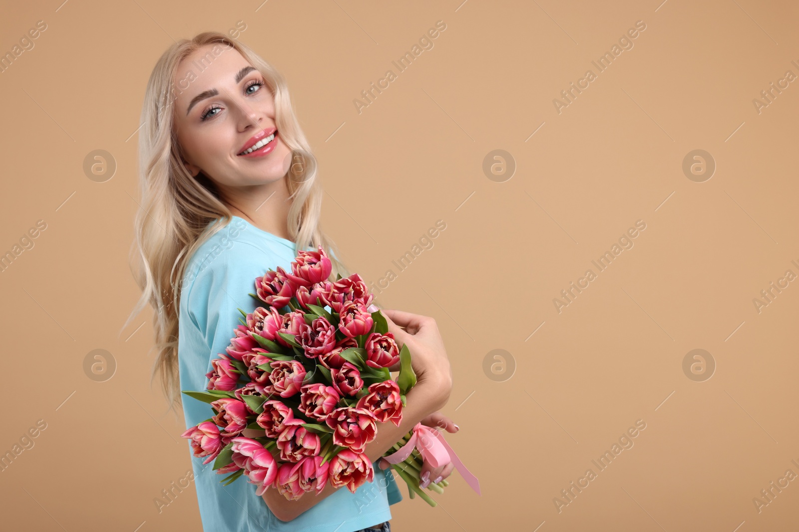 Photo of Happy young woman with beautiful bouquet on beige background