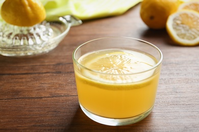 Photo of Glass with fresh lemon juice on wooden table